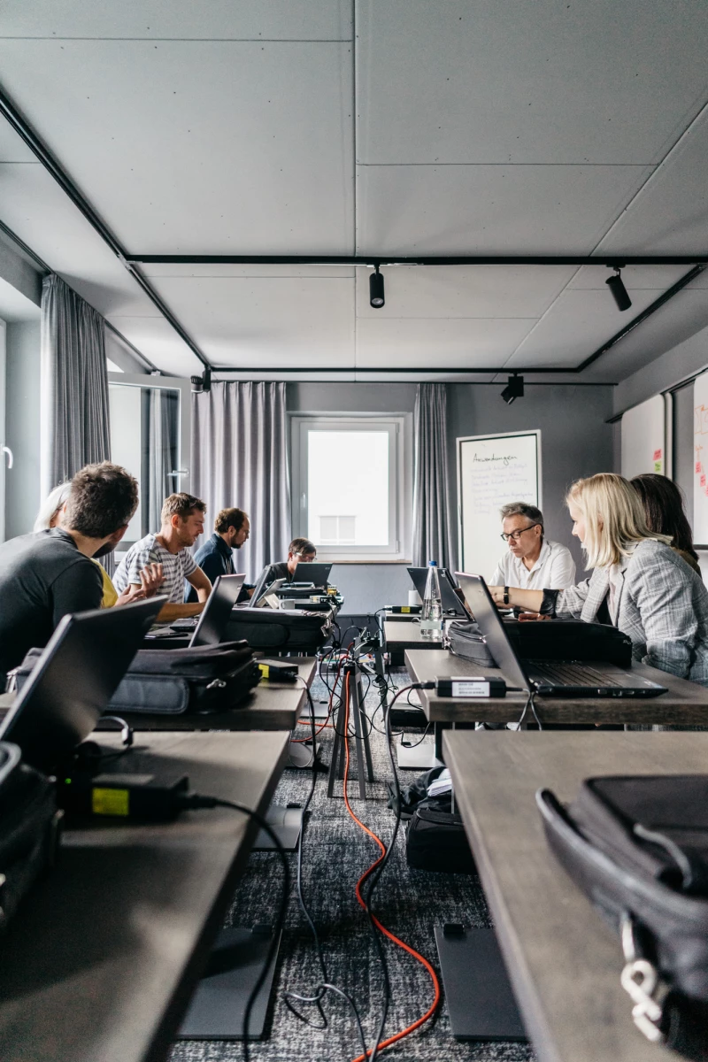 Meetingraum im Schwarzen Adler mit Teilnehmern und Laptops.