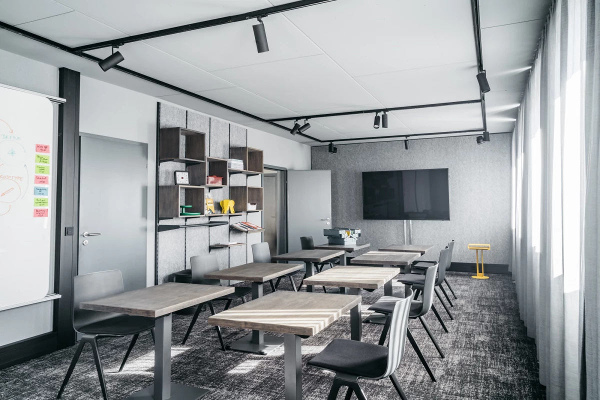 Moderner Konferenzraum im Schwarzen Adler mit höhenverstellbaren Tischen und Stühlen.