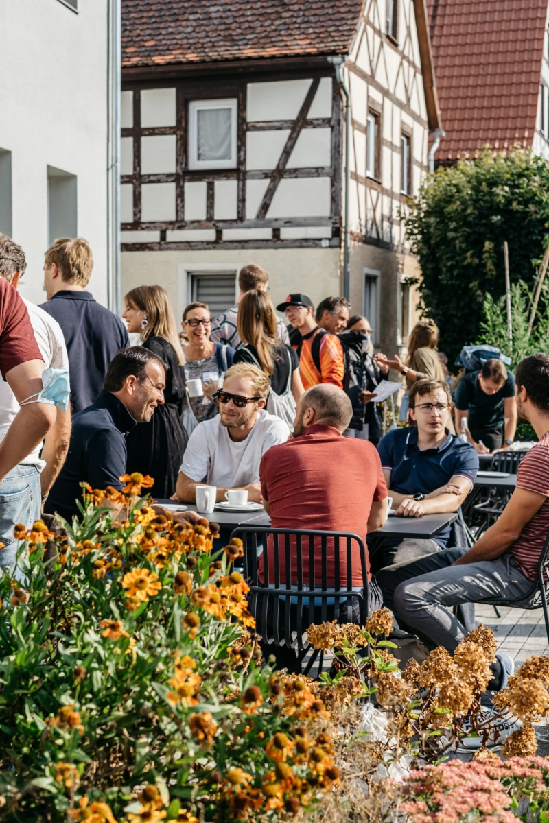 Konferenzgäste genießen sonnigen Tag auf Terrasse des Schwarzen Adlers.