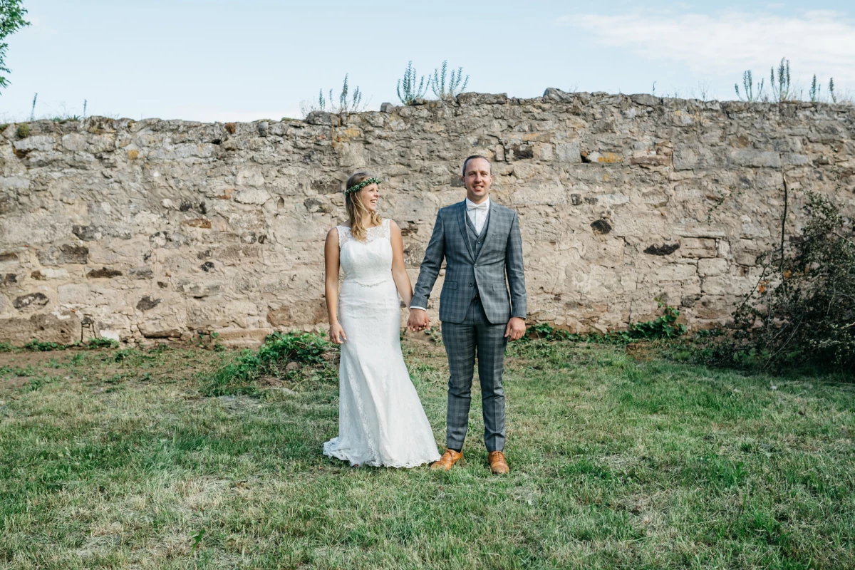 Brautpaar auf der Obstwiese am Gutshof Neun vor historischer Stadtmauer.